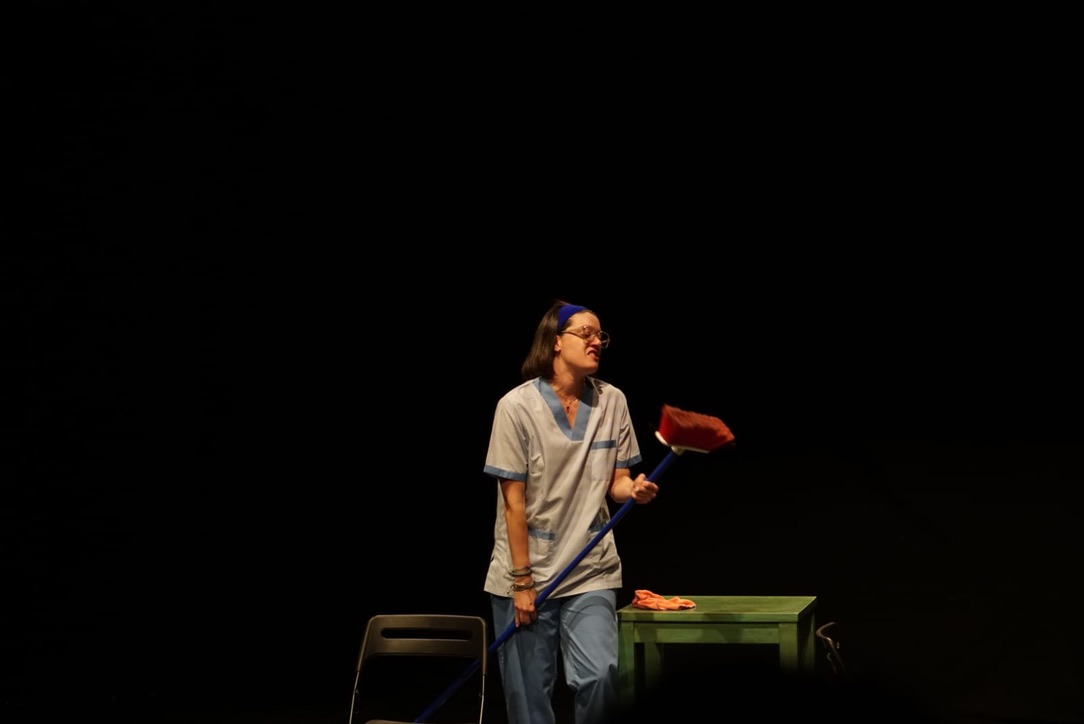Mar en escena con una escoba junto a una mesa